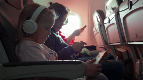 Family-of-mother-and-two-kids-with-gadgets-in-the-plane