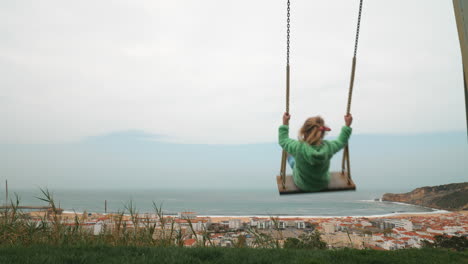 Little-girl-swinging-against-the-scene-of-Nazare-coast-in-Portugal