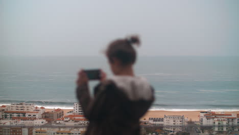 Boy-taking-pictures-of-scenic-Nazare-coast-and-ocean-Portugal
