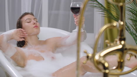 Adorable-woman-drinking-wine-in-bath-with-foam-bubbles-wellness-and-spa-relax.