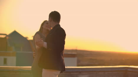 Two-lovers-embracing-dancing-on-top-of-a-skyscraper-overlooking-the-city-at-sunrise-sunset.-Romantic-setting