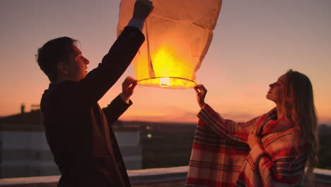 A-man-and-a-girl-in-a-plaid-launch-a-sky-lantern-on-the-roof.