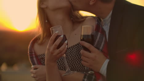close-up-on-hands-of-women-holding-red-wine-glasses-on-balcony-during-sunset-celebration-concept