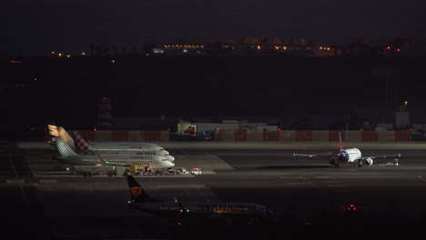Side-view-of-planes-on-the-runway-at-the-airport-at-night