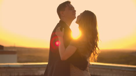 Two-lovers-embracing-dancing-on-top-of-a-skyscraper-overlooking-the-city-at-sunrise-sunset.-Romantic-setting