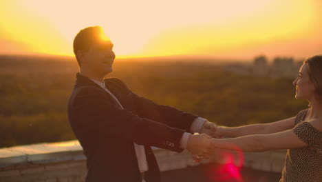 A-man-and-a-woman-in-love-dance-standing-on-the-roof-of-a-building-at-sunset-looking-at-each-other.