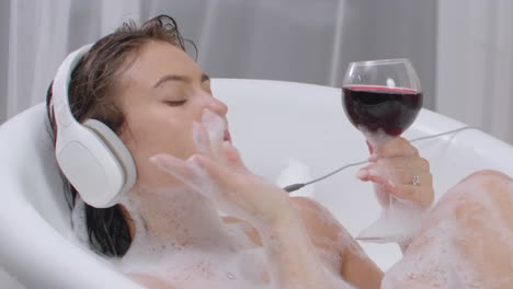 Drink-red-wine-lying-in-a-hot-bubble-bath-and-listen-to-music-for-relaxation.