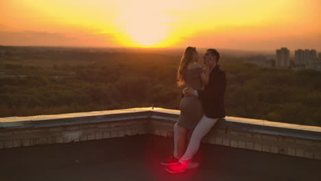 Hugging-standing-on-the-roof-at-sunset.-Summer-roof-at-sunset.-A-man-with-a-girl-came-on-a-romantic-date-on-the-roof.