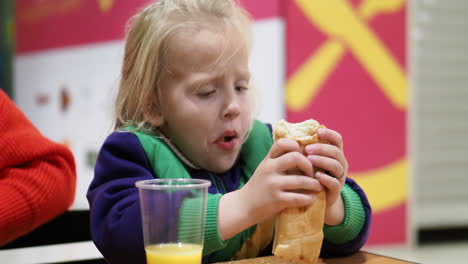 Kid-eating-hot-dog-with-orange-juice