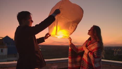 To-launch-a-sky-lantern-at-night-on-the-roof.-The-lovers-are-together.-Chinese-sky-lanterns.