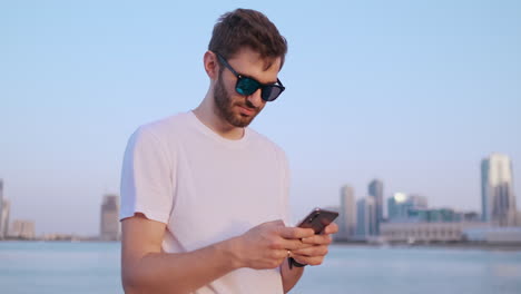 Camera-moves-around-handsome-young-man-as-he-uses-his-phone.-Portrait.-Blurred-background.