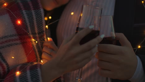 Close-up-hands-holding-glasses-of-wine-at-sunset.-Strong-romantic-feelings.-Sunset-date-on-the-roof.