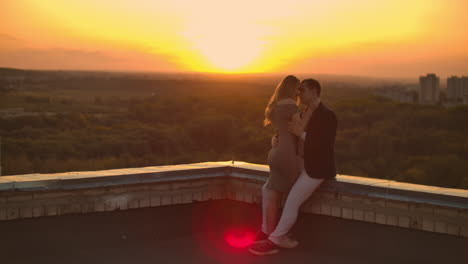 Young-couple-in-love-standing-on-the-roof-hug-and-closely-look-at-each-other.-Romantic-evening-on-the-roof-of-the-building.-A-date-on-the-roof-of-a-building-love.-Slow-motion