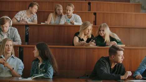 The-group-of-cheerful-happy-students-sitting-in-a-lecture-hall-before-lesson.-The-group-of-cheerful-students-sitting-in-a-lecture-hall-before-lesson.