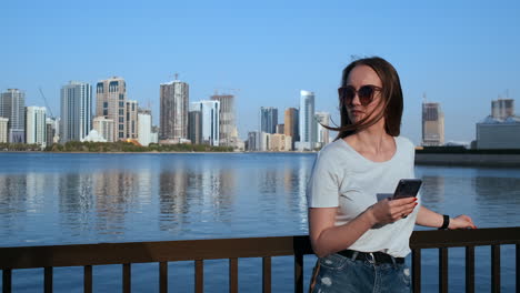 A-girl-with-long-hair-dials-a-message-on-the-smartphone-at-the-quay-of-Dubai