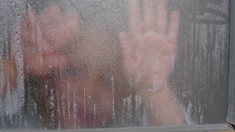 Kid-wiping-steamy-window-to-look-outside