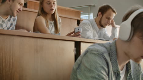 Hübsche-Studentinnen-Benutzen-Smartphones,-Schauen-Auf-Den-Bildschirm,-Reden-Und-Lachen-An-Schreibtischen-In-Der-Universität.-Social-Media,-Internet,-Millennials-Und-Bildungskonzept