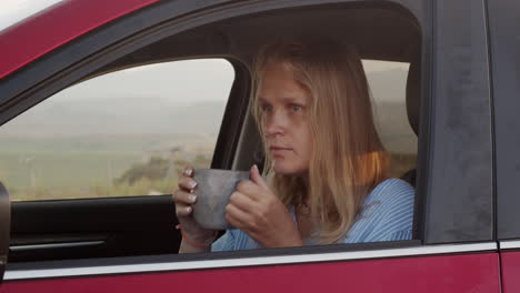 Woman-on-a-road-trip-making-a-stop-to-rest-with-tea-and-phone