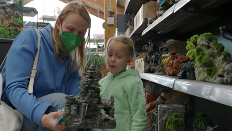 Mother-and-child-choosing-decoration-for-aquarium-in-store