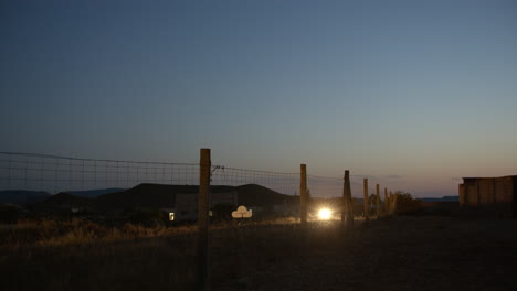 Few-cars-on-remote-country-road-along-the-fenced-area-in-the-dusk