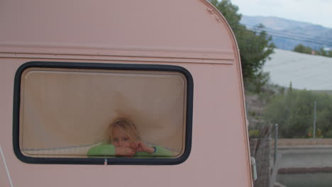 Little-Blonde-Girl-Peeking-Out-of-Camper-Van-Window