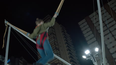 Boy-having-fun-on-bungee-trampoline-in-amusement-park-at-night