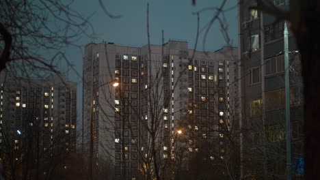 Evening-view-of-apartment-houses-with-lights-and-bare-trees-around