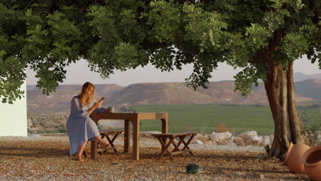 Woman-villager-with-phone-and-tea-resting-under-the-tree