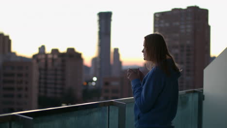 Urban-woman-drinking-tea-on-the-balcony-in-early-morning
