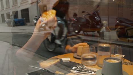 Woman-eating-at-a-table-in-a-cafe---through-the-glass