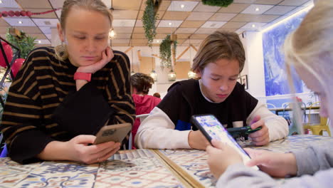Mom-and-kids-are-on-their-phones-in-a-cafe---2