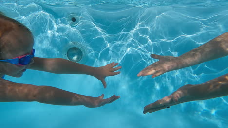 Girl-and-mother-touch-hands-underwater