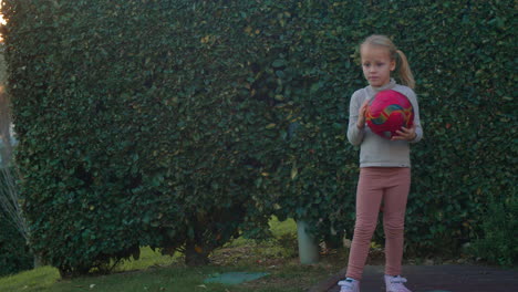 Child-Playing-with-Ball-in-Leafy-Backyard