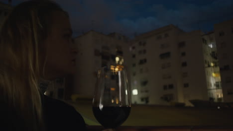A-young-woman-is-holding-a-glass-of-wine-in-a-balcony