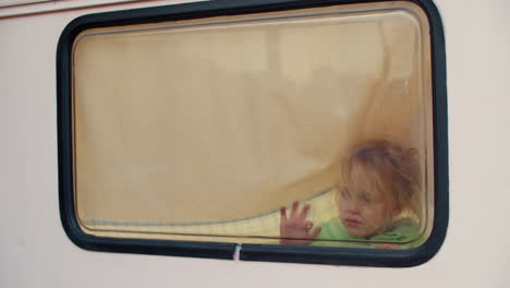 Kleines-Mädchen-Malt-Mit-Den-Fingern-Auf-Das-Fenster-Im-Lieferwagen