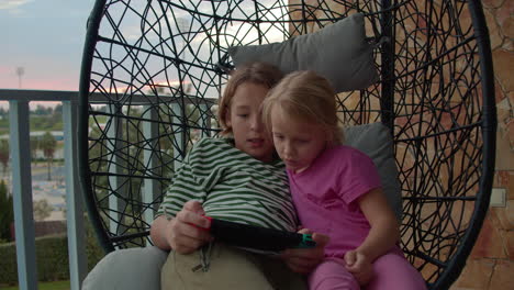 Siblings-playing-console-on-balcony