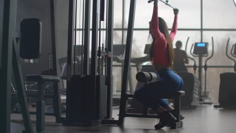 The-fitness-instructor-woman-performs-power-training-in-the-gym.-She-pumps-her-back-and-arms-for-a-muscular-body.