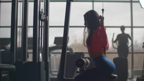 The-girl-performs-a-personal-training-on-the-muscles-of-the-back.-She-starts-a-barbell-with-a-weight-behind-her-back.