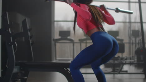 The-girl-trains-the-muscles-of-the-thigh-and-buttocks.-She-does-squats-using-a-barbell-to-load-for-better-results.