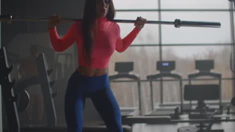 A-young-woman-performs-a-circular-exercise-on-her-thigh-muscles.-She-performs-squats-to-work-out-the-buttocks-with-a-barbell.