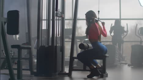The-fitness-instructor-girl-performs-power-training-in-the-gym.-She-pumps-her-back-and-arms-for-a-muscular-body.