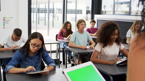 Teacher-uses-tablet-in-high-school-class,-over-shoulder-view
