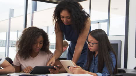 Teacher-helping-teenage-schoolgirls-with-technology-in-class