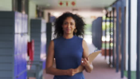Black-female-teacher-walks-into-focus-in-school-corridor