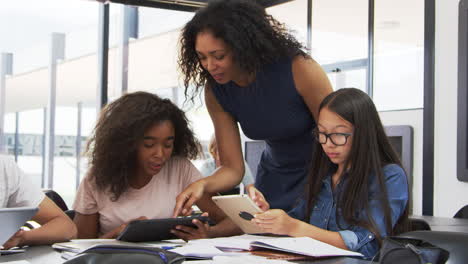 Teacher-helping-teenage-schoolgirls-with-technology-in-class