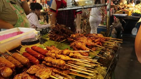 Verschiedene-Grillspieße-Mit-Gegrilltem-Fleisch-Auf-Einem-Streetfood-Wagen-Auf-Dem-Thailändischen-Nachtmarkt