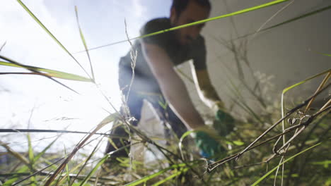 low-angle-view-from-the-grass-field-of-young-male-working-in-his-garden-preparing-the-soil