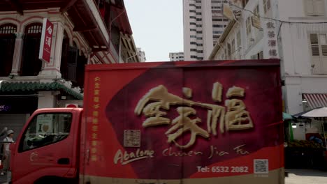 A-slow-motion-shot-of-a-delivery-truck-passing-by-the-old-heritage-buildings-on-Temple-Street-Chinatown,-Singapore