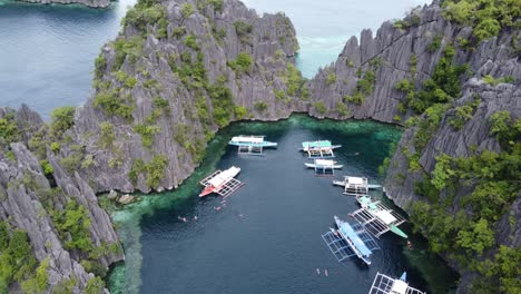 People-and-island-hopping-tour-boats-in-clear-blue-water-of-twin-lagoon,-coron