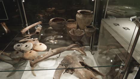 ancient-Bones,-pots-and-skulls-in-glass-case-at-the-exhibition-in-the-museum-of-Biskupin,-Poland